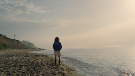 fashionable woman walking on sea shore. relaxed girl enjoying ocean landscape.