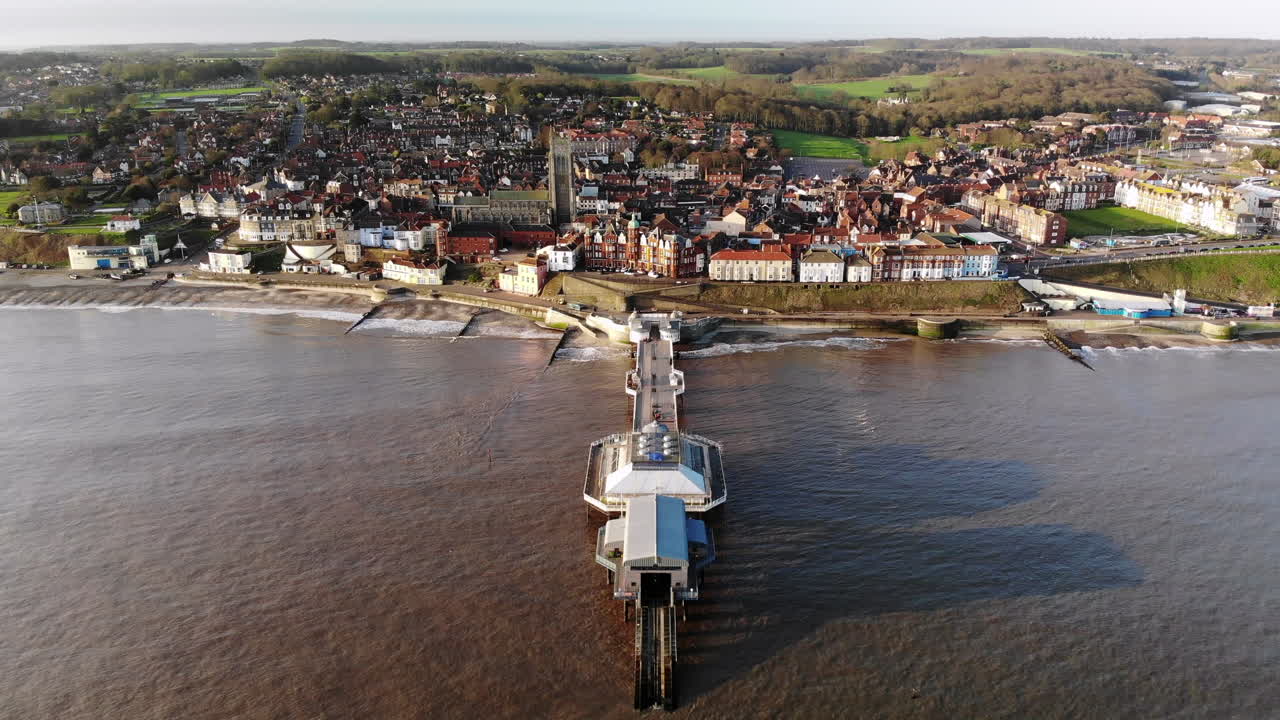 Drone footage from the sea flying over the pier at Cromer, Norfolk towards the town in early morning
