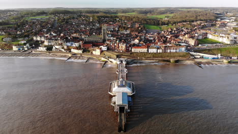 drone footage from the sea flying over the pier at cromer, norfolk towards the town in early morning