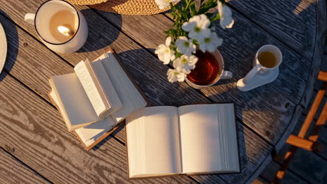cozy outdoor reading scene with books, candle, and tea on a rustic wooden table