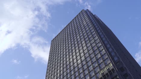 high rise building in one of the city in tokyo, japan with bright blue sky above and white clouds