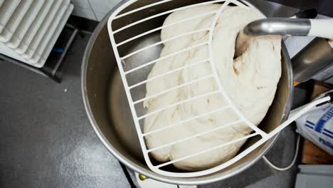 overhead view of raw dough being mixed by a machine. top down view of industrial dough mixing machine in a restaurant