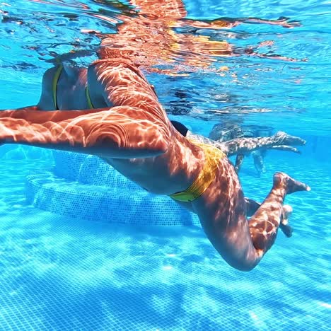 woman swimming underwater in blue pool
