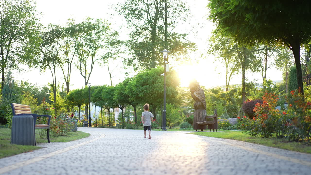 Lovely barefoot little kid runs by the paved alley. Happy time spending in the green park in summer.