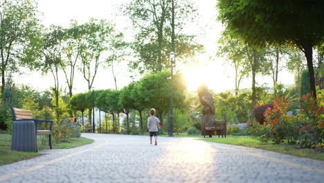 lovely barefoot little kid runs by the paved alley. happy time spending in the green park in summer.