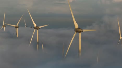 aerial drone shot flying over wind farm above the clouds and mist