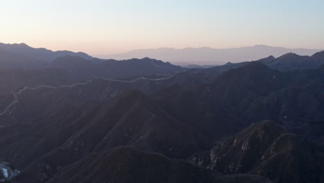 Aerial-Shot-of-Great-Wall-of-China-Winding-Through-Mountains-at-Sunset