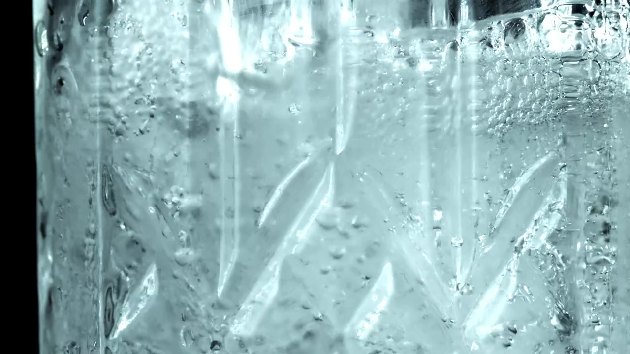 Scatto macro di bolle effervescenti in un bicchiere di liquido trasparente