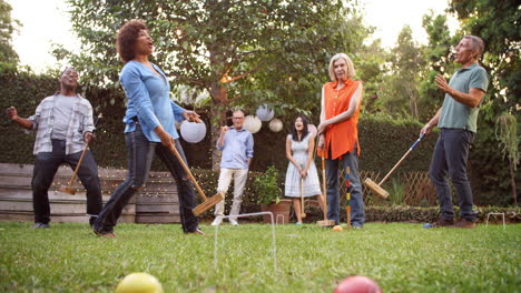 group of mature friends playing croquet in backyard together