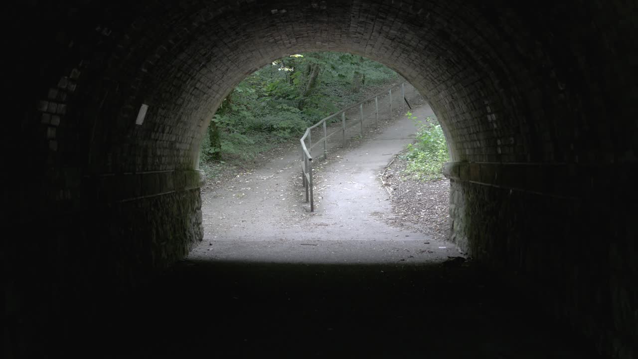 Bright park walk at the end of a dark tunnel