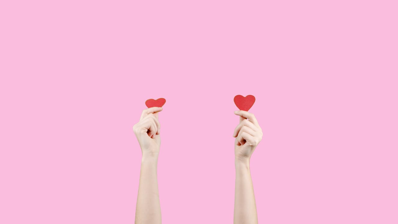 blogger mujer sostiene en las manos pequeños corazones rojos en fondo rosa. como en la red social. día de san valentín, día internacional de la mujer, amor