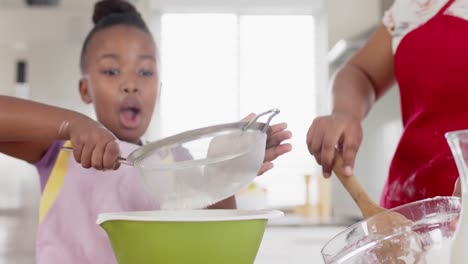 Happy-unaltered-african-american-mother-and-daughter-baking-in-kitchen,-in-slow-motion