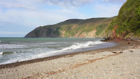 Wellen-Brechen-In-Die-Kiesküste-Des-Blacklands-Beach-In-Lynmouth-Und-Zeigen-Die-Reichweite-Der-Gezeiten-Mit-Einer-Reihe-Von-Treibgut-Und-Strandgut-Hoch-Am-Strand