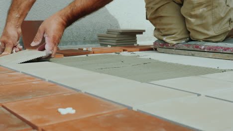 the builder puts ceramic tiles on the floor on the open veranda