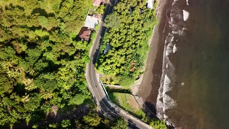 bird eyes view of flying up via drone over the highway beside the beach in bali 4k and 30 fps