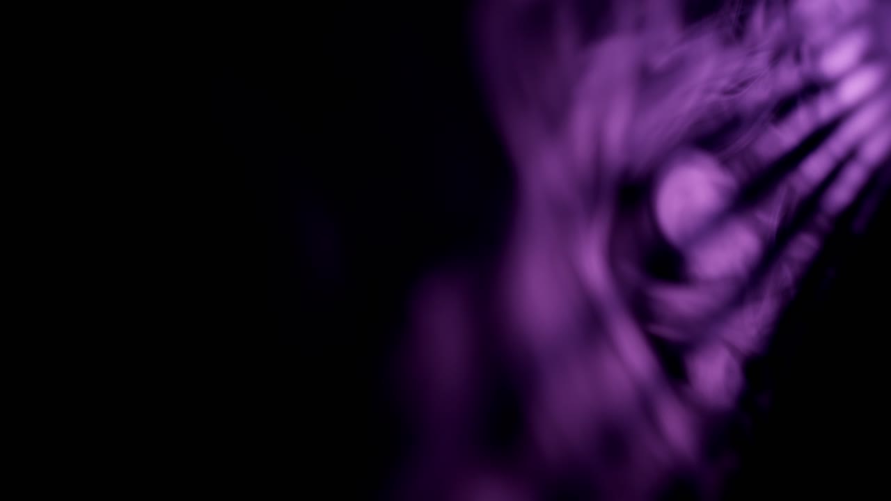 Abstrakt lilla lys, der filtrerer gennem teksturerede overflader og skaber skiftende skygger og lysende mønstre i mørket.