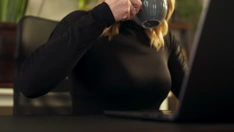 Medium shot of blond caucasian woman's hand taking a cup of tea and drinking, interior