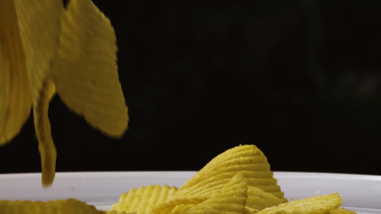 Close Up of Potato Chips Crinkle Cut Crisps with Black Background Slow Motion - 4K Food Clip