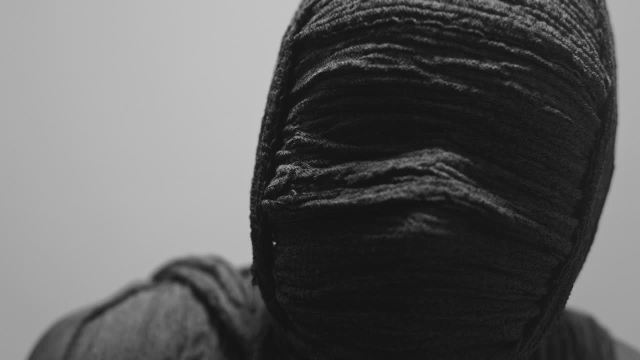 Una mummia di donna su uno sfondo bianco guarda in camera