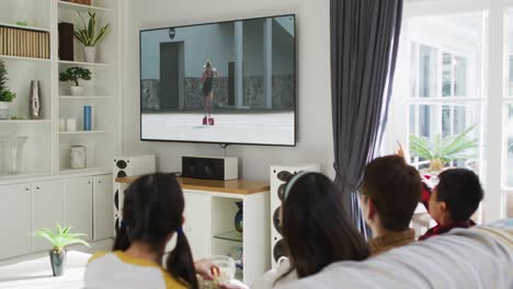 Composite-of-happy-family-sitting-at-home-together-watching-athletics-running-event-on-tv