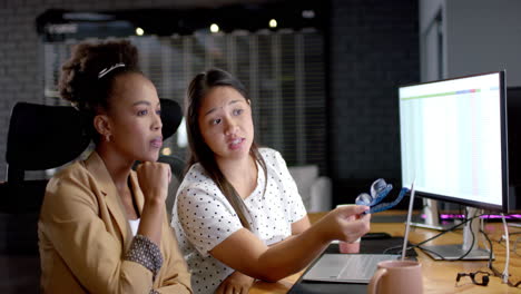 young african american woman and biracial woman discuss business work in an office