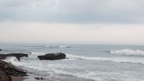 rough waves crashing on the rocks and beach in bali, indonesia