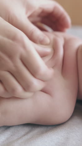 small newborn boy with short thin fair hair lies on stomach on changing table and nurse makes back massage close view