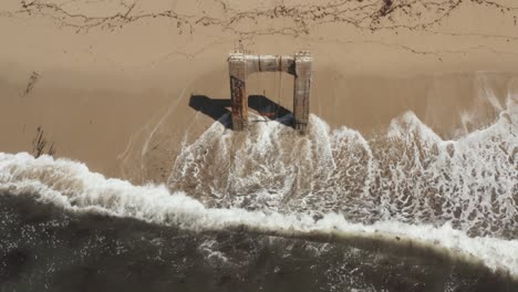 aerial view of old broken pier made of cement in the middle of the ocean near santa cruz california