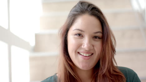 Portrait-of-happy-plus-size-biracial-woman-smiling-in-sunny-room-at-home,-slow-motion