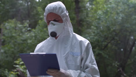 scientist in hazmat suit taking notes in the forest