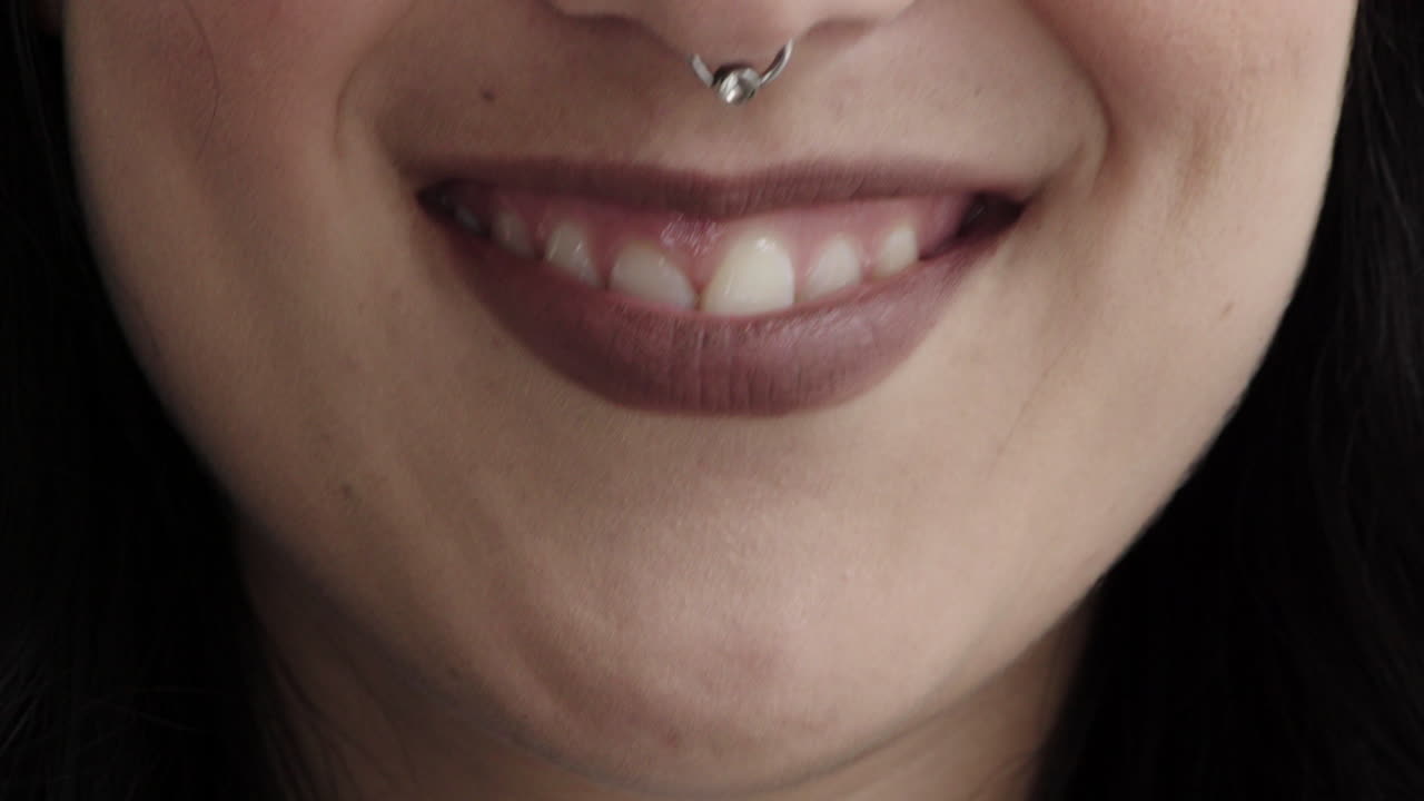 вблизи женщина улыбается, счастлива, носит кольцо на носу, макияж, косметику, женскую красоту.