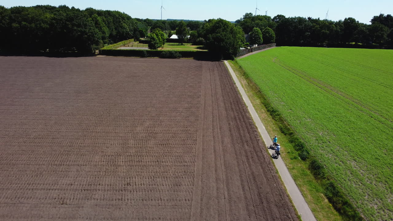 People Biking Through Rural Fields
