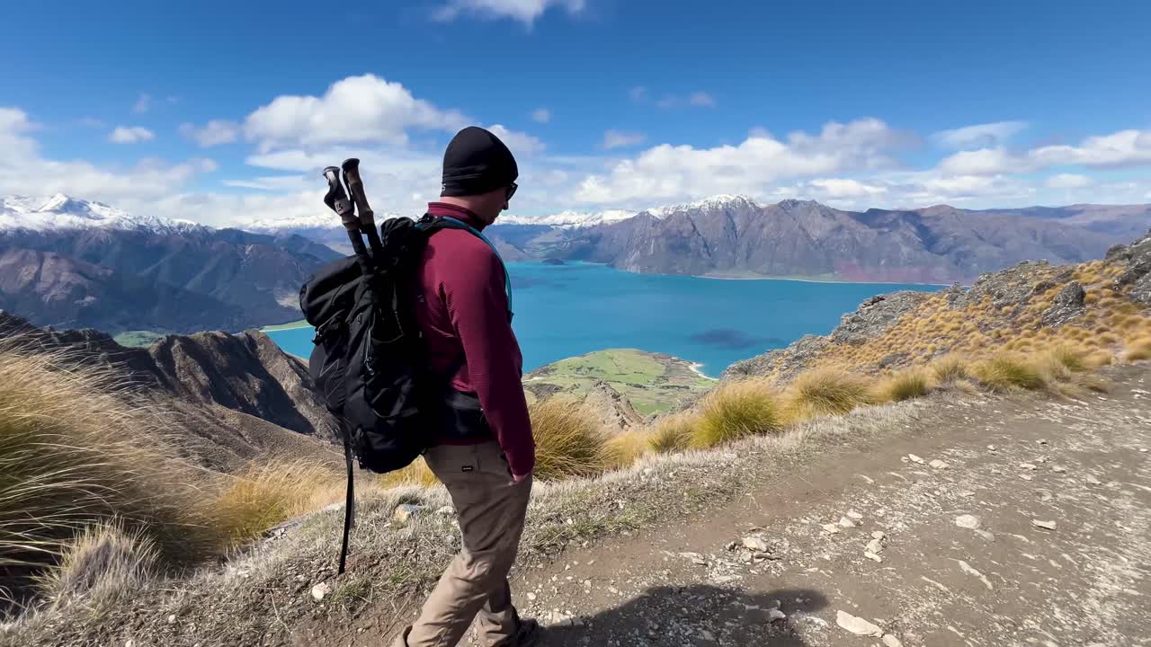 Hiker enjoys stunning lake and mountain views on Isthmus Peak, Otago, New Zealand