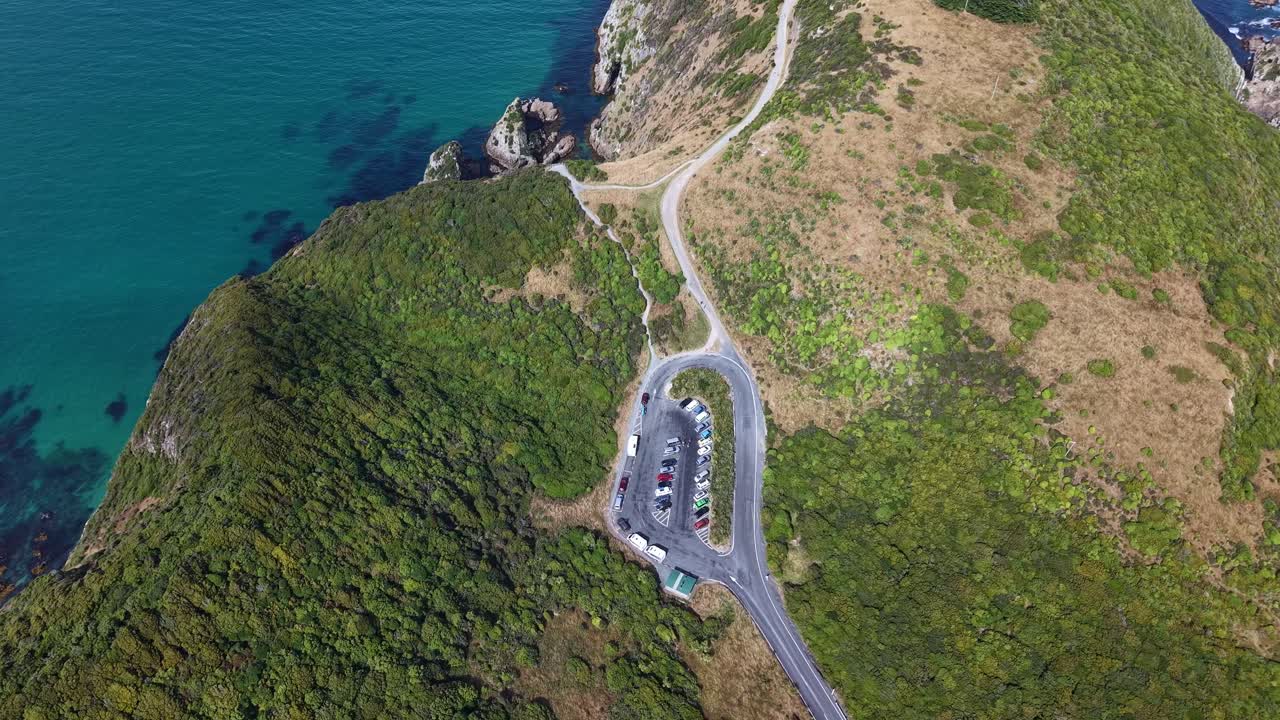 Aerial top down drone descending over Nugget Point headland, cliffs, ocean and carpark