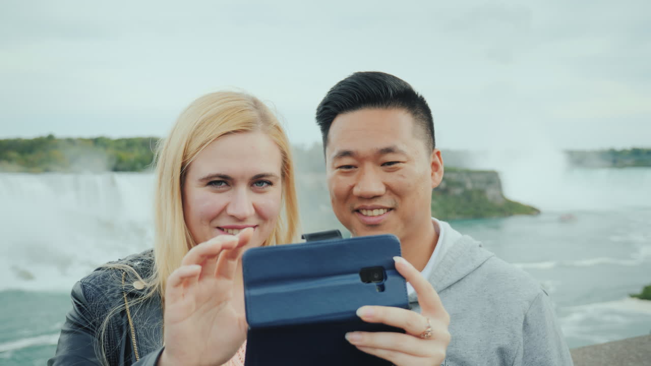 ナイアガラの滝で携帯電話で自撮りをする活動的な夫婦のクローズアップ