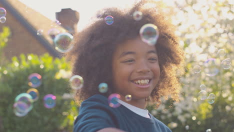 smiling boy outdoors having fun playing with bubbles in garden