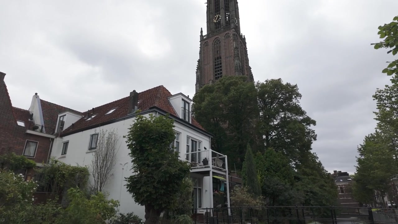 Blick auf den Onze Lieve Vrouwetoren Turm mit der grünen Umgebung von Amersfoort und blauem Himmel im Hintergrund.