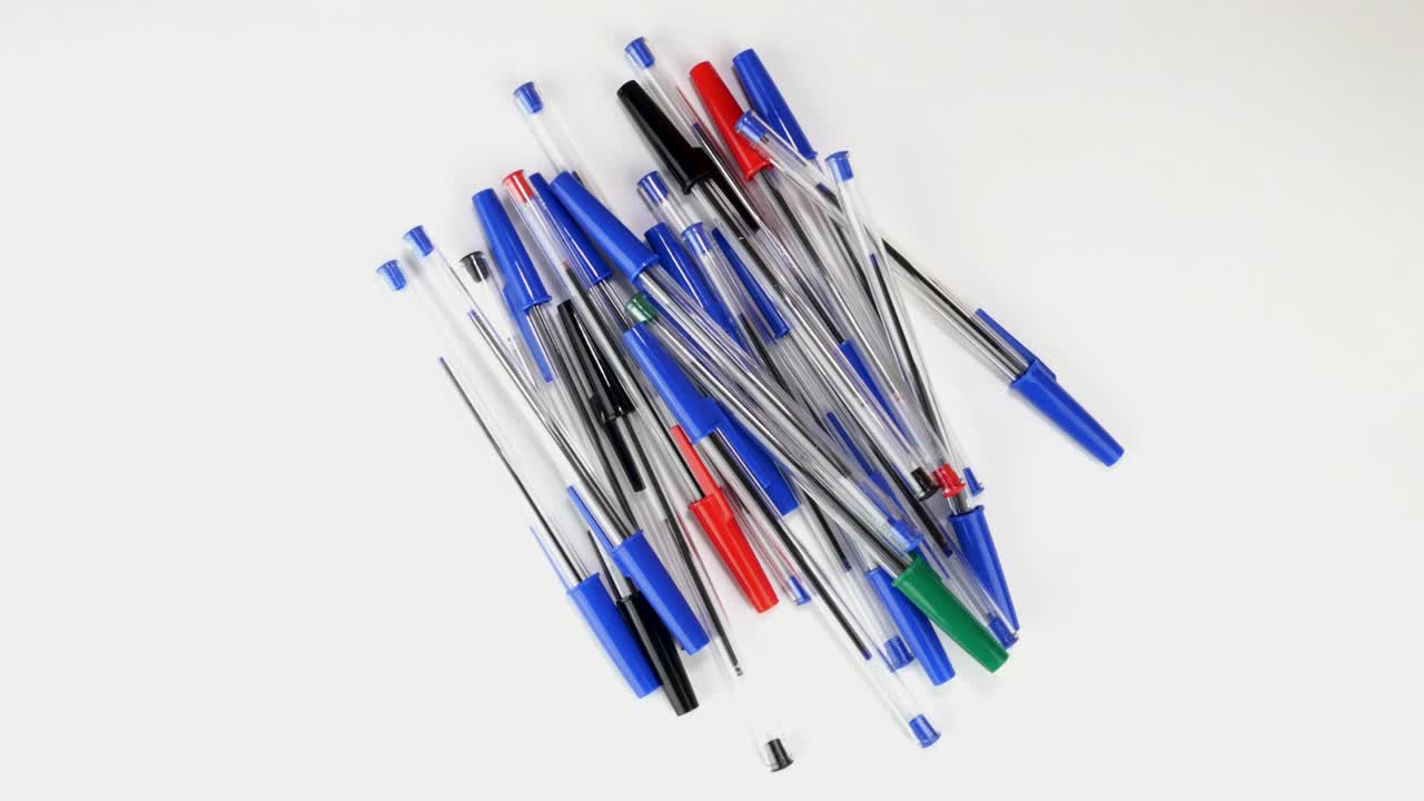 un montón de bolígrafos coloridos girando giran lentamente en la pantalla blanca en la oficina o la escuela.
