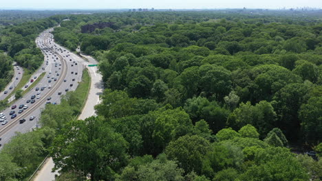 an aerial view over a busy parkway next to a large park with green trees