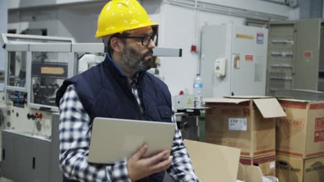 Serious-engineer-walking-with-laptop-at-factory