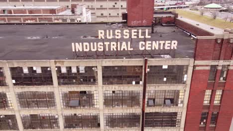 logo sing of aged russel industrial center building complex in michigan, aerial side fly shot