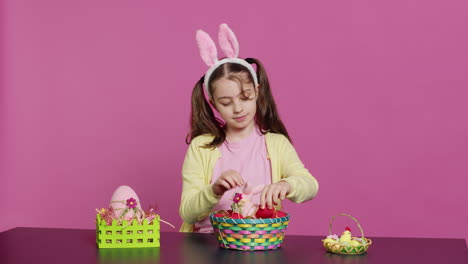 excited young girl arranging painted eggs in a basket to prepare for easter