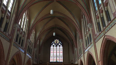 arch shaped stained glass panel and the rib vault ceiling at gouwekerk church in gouda, netherlands