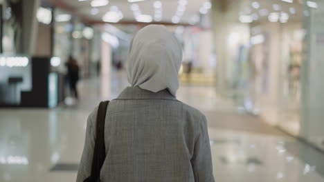 Muslim-woman-with-hijab-in-coat-walks-along-shopping-center