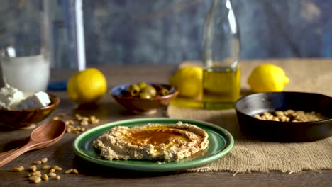 Warme,-Flache-Folie-Nach-Rechts,-Die-Eine-Auswahl-An-Gerichten-Aus-Dem-Nahen-Osten-Mit-Oliven,-Pinienkernen,-Hummus,-Feta-Und-Ouzo-Zeigt