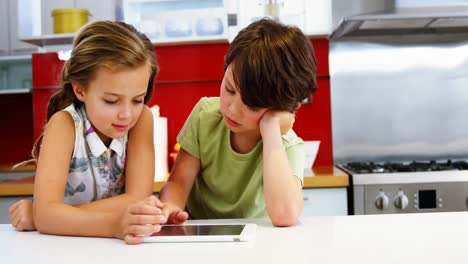 hermanos que usan tabletas digitales en la cocina