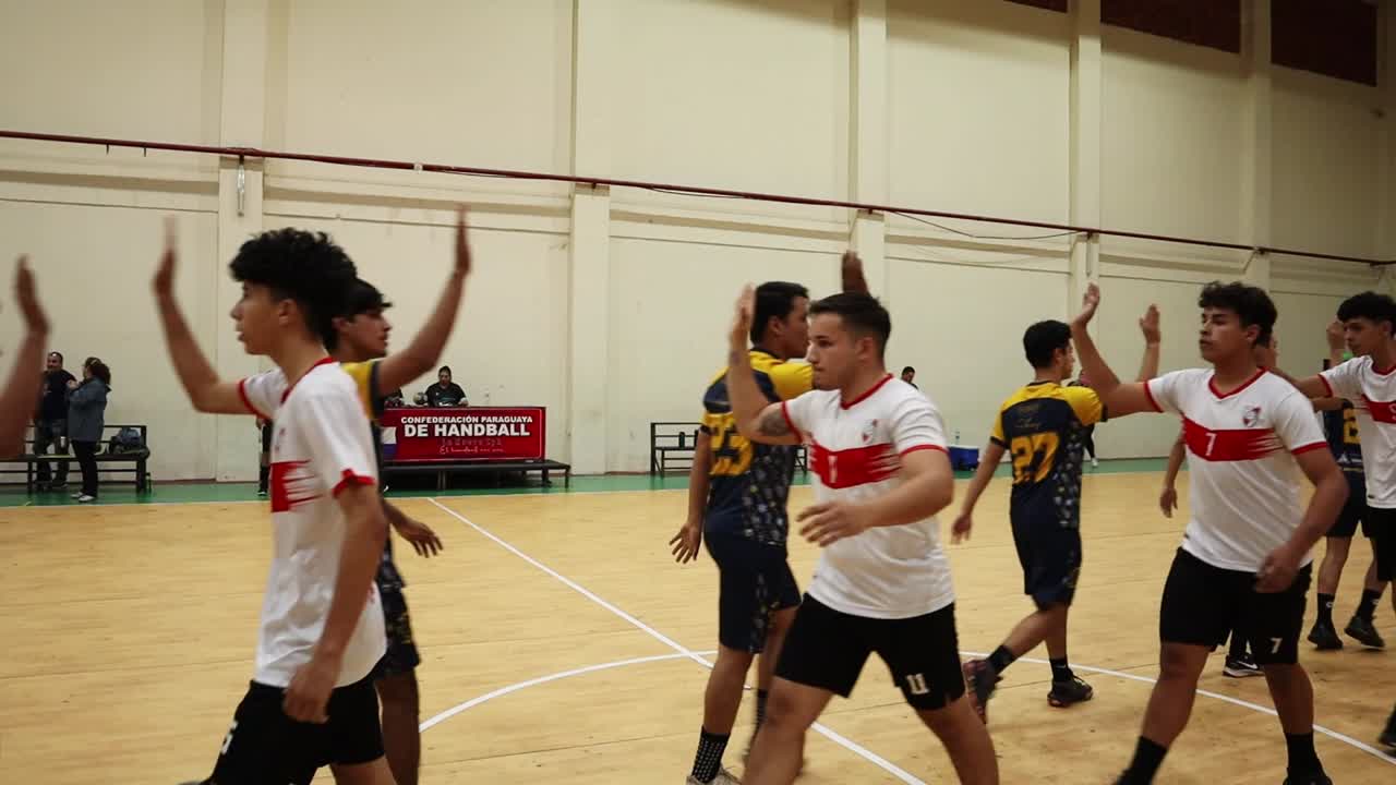 Editorial footage of youth handball teams shaking hands at center court before the start of their game. Players exchange handshakes as a gesture of sportsmanship before competition