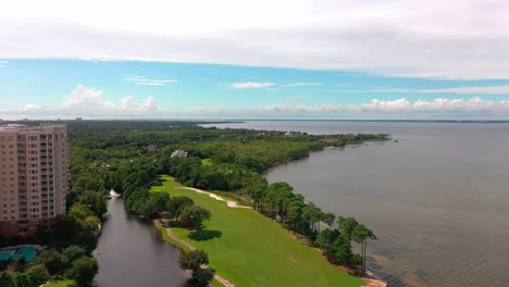 drone aerial view flying past the one water place condominium in destin florida next to the mid bay bridge