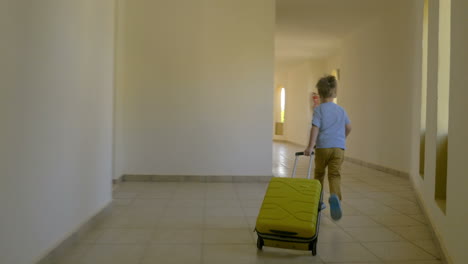 child with rolling bag running along the hotel corridor