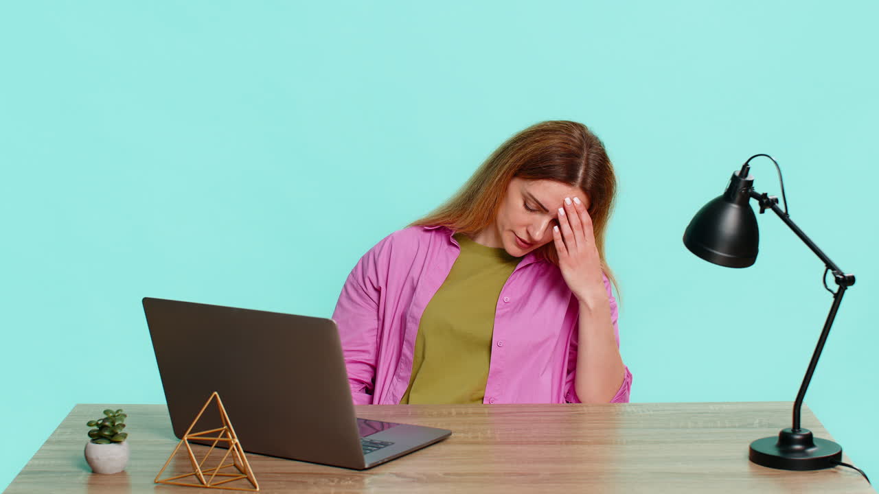 Adult woman sitting at table looking upset and irritated after system crash or file loss on laptop